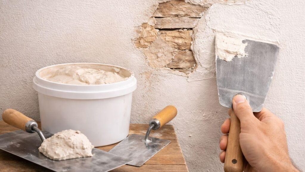 Wall repair material plaster being applied with a trowel to repair a damaged wall surface with exposed lath for a durable finish