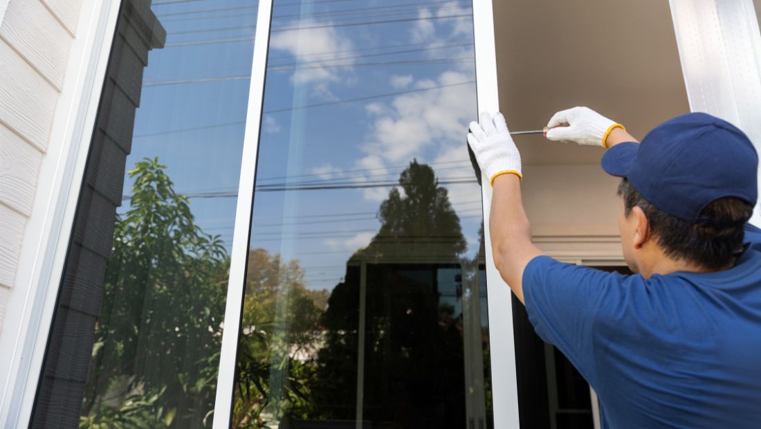 Technician sealing a window frame from outside to fix foggy windows, preventing moisture buildup and improving energy efficiency.