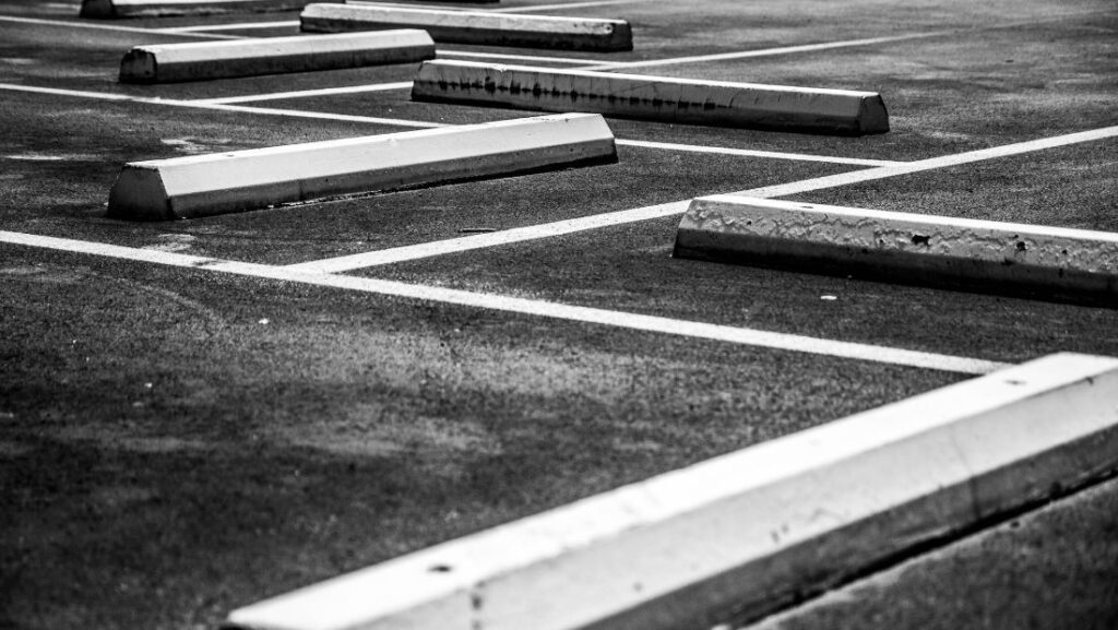 Empty parking lot showing concrete wheel stops and painted parking lines on asphalt surface